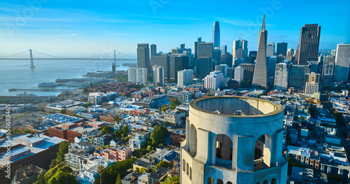 Aerial of roof of Coit Tower overlooking downtown skyscrapers and Oakland Bay Bridge