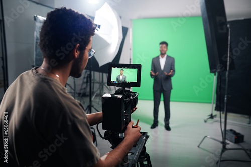 Rear view of professional cameraman using camera to shoot TV program in studio