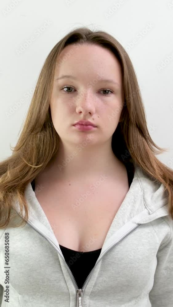 put on a sports outfit, young teenage girl is preparing for sports, a black top and a gray sports jacket in the studio, beauty, grooming, straighten her hair, button up her jacket put on a sports outfit, young teenage girl is preparing for sports, a black top and a gray sports jacket in the studio, beauty, grooming, straighten her hair, button up her jacket