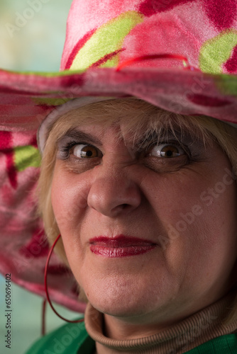 Clown in a hat. The buffoon grimaces and entertains. Portrait of a dressed up artist.