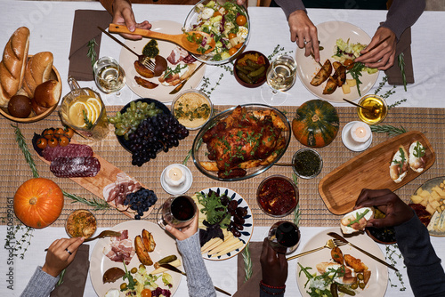 Top view background image of people at festive dinner table for Thanksgiving enjoying roasted dishes, copy space