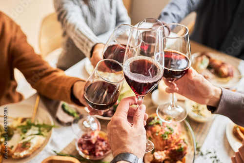 Close up of people toasting with red wine glasses at festive dinner table, copy space