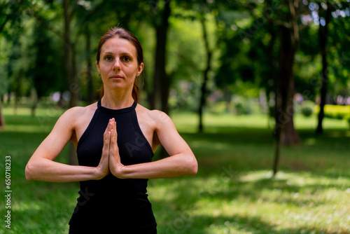 an experienced female instructor meditates in the park practices yoga does stretching and exercises for different muscle groups