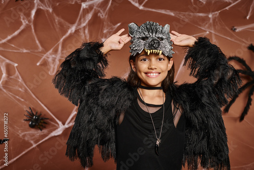 close up smiling preteen girl with raised hands in black faux fur attire, Halloween concept