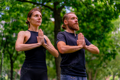 portrait of a couple practicing yoga in a city park doing meditation exercises with namaste gestures people focus on mental and spiritual health