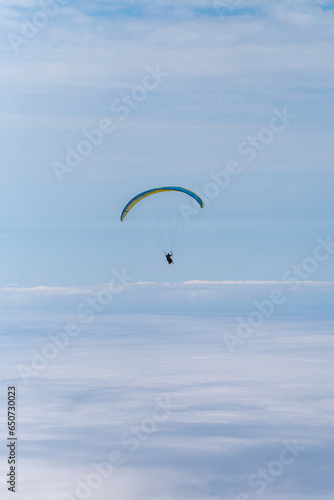 paragliding in the blue sky above the clouds