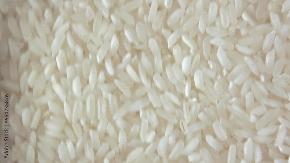 Dry Uncooked White Rice Background Slowly Moving Upward - Top View. Scattered Raw Long Grain Rice. Asian Cuisine and Culture. Healthy Eating Ingredients. Diet Food Dry Uncooked White Rice Background Slowly Moving Upward - Top View. Scattered Raw Long Grain Rice. Asian Cuisine and Culture. Healthy Eating Ingredients. Diet Food