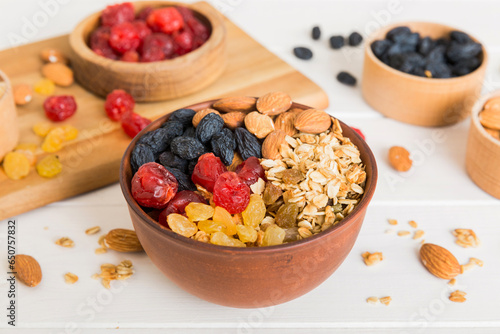 Fototapeta Naklejka Na Ścianę i Meble -  Cooking a wholesome breakfast. Granola with Various dried fruits and nuts in a bowl. The concept of a healthy dessert. Flat lay, top view with copy space
