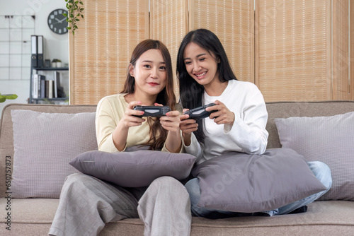 Young Asian couple playing video games at home in the living room having fun.