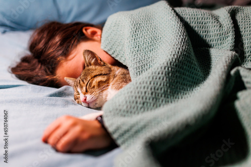 boy falls asleep and hugs his cat, who sleeps with him under the covers. children and pets. the cat sleeps with the baby.