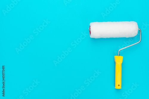 Clean paint roller on the turquoise blue background with copy space.