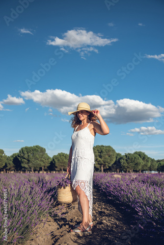 Woman with a basket and a pamela in a field of lavender.