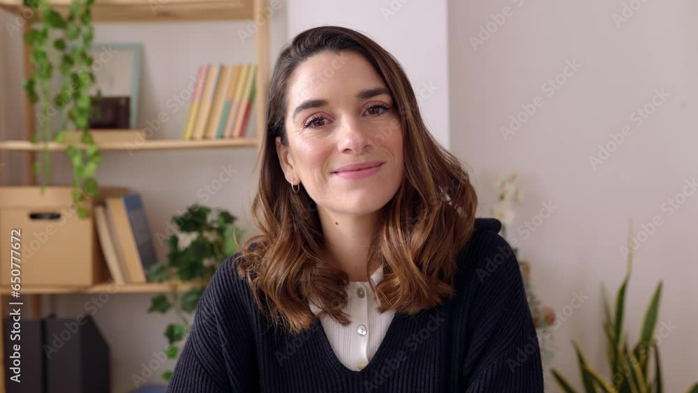 Smiling portrait of cheerful young adult woman looking at camera sitting at home office. Headshot of millennial female feeling positive and satisfied indoors. Smiling portrait of cheerful young adult woman looking at camera sitting at home office. Headshot of millennial female feeling positive and satisfied indoors.