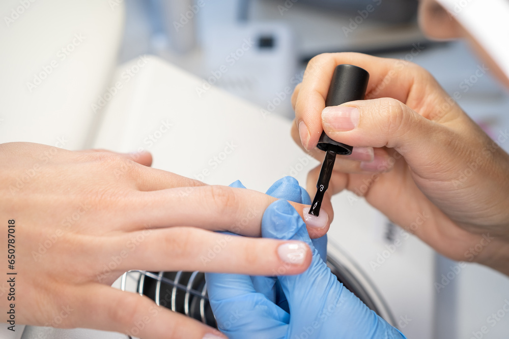Nail care procedure in a beauty salon. Female hands and tools for manicure, process of performing manicure in beauty salon. Concept spa body care. Gloved hands of a skilled manicurist cutting cuticles Nail care procedure in a beauty salon. Female hands and tools for manicure, process of performing manicure in beauty salon. Concept spa body care. Gloved hands of a skilled manicurist cutting cuticles