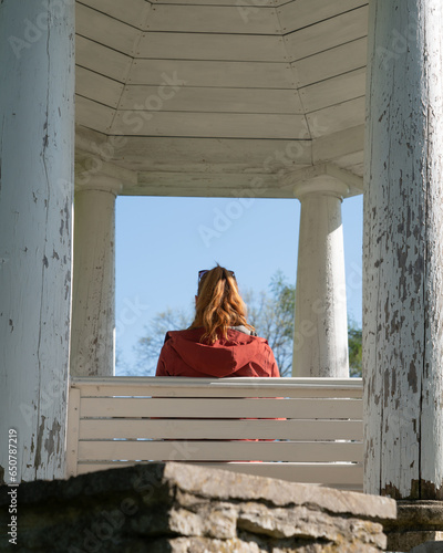 Woman sitting on top of the tower under amazing wooden paviljon. Gazebo over looking  the river in the garden of the Vihula manor. Sunny summer day.  photo