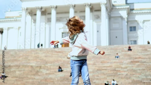 Adorable preschooler girl jumping near Helsinki Cathedral (Helsingin tuomiokirkko) on Senaatintori in Helsinki, Finland. photo