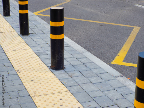 Fotografie Yellow pavement for the blind on the floor on the bus stop with road bollards
