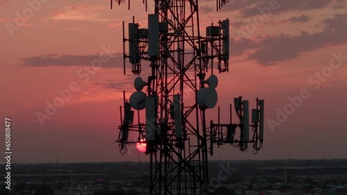 Television or radio telephone tower in a cityscape at sunset time. Aerial zoom view