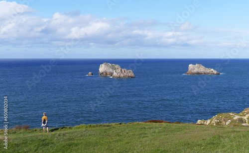 Woman looking at the ocean in the natural park of Liencres, Cantabria, Spain photo