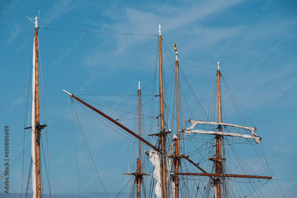 Collection of tall wooden sail masts against a bright blue sky. Collection of tall wooden sail masts against a bright blue sky.