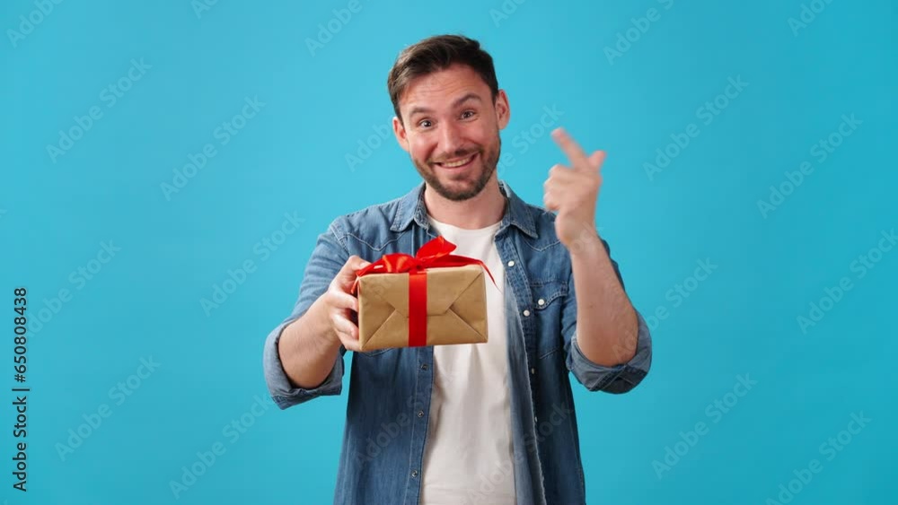 Man stands up and gives gift in box with red ribbon Man stands up and gives gift in box with red ribbon