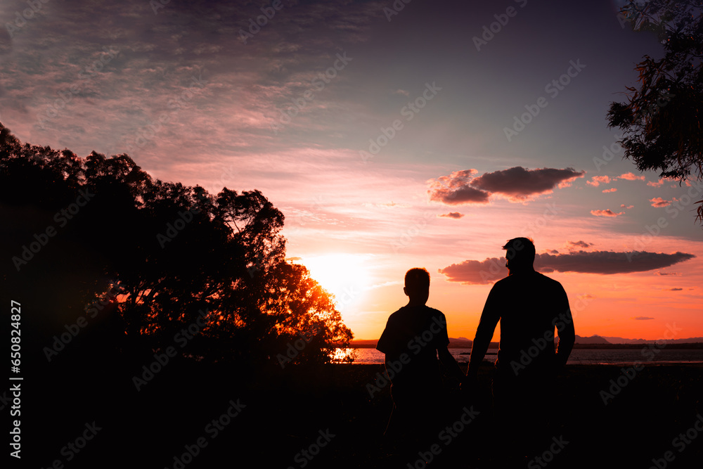 silhouette of father and son against nature background with raised hands,concept of family success silhouette of father and son against nature background with raised hands,concept of family success