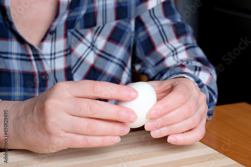 Hands of an elderly woman showing a white boiled egg