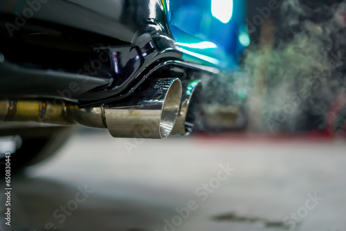 Close-up of the exhaust pipe emitting smoke from a chameleon-colored luxury car in the process of car washing © Guys Who Shoot