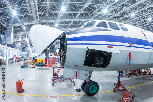 White transport turboprop airplane in the hangar. Aircraft under maintenance. Checking mechanical systems for flight operations