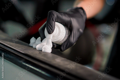 Close-up of a car wash worker applying plastic wash foam while cleaning the door card of a luxury car during the detailing process