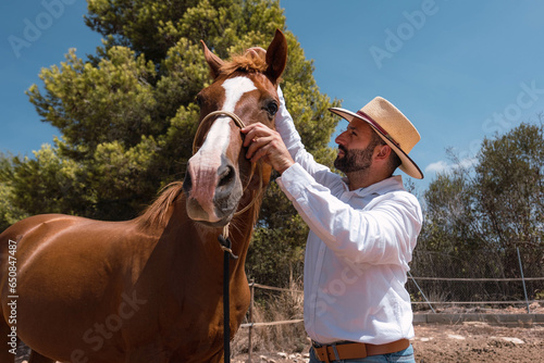 western man grooming and feeding his horses on his ranch