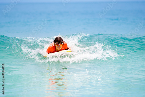 Photography Child surfing on tropical beach. Surfer in ocean.