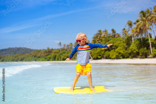 Photography Child surfing on tropical beach. Surfer in ocean.
