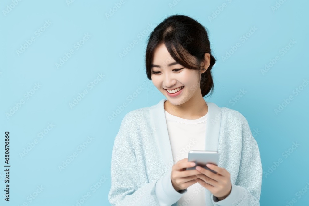 Cute Japenese Fictional Woman Using Phone and Smiling. Isolated on a Plain Light Blue Background. Generative AI. Cute Japenese Fictional Woman Using Phone and Smiling. Isolated on a Plain Light Blue Background. Generative AI.