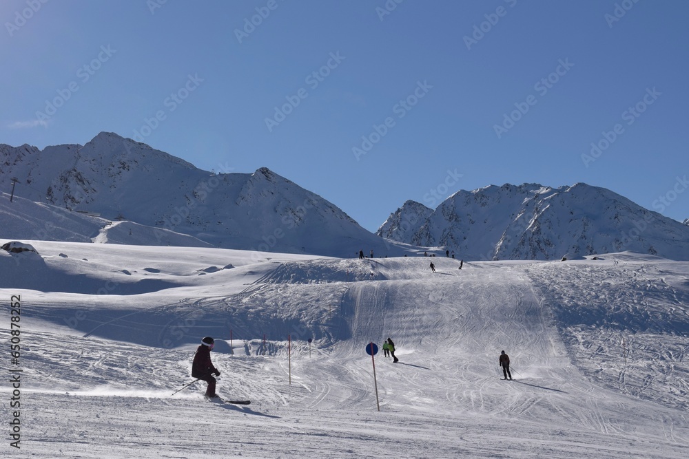 Skiers and snowboarders in Hochgurgl on a beautiful sunny day, perfect conditions for winter sport, skiing and snowboarding in the snowcapped alpine mountains in the Ötztal valley, Tyrol, Austria.