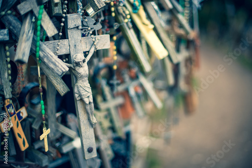 Selective focus shot of a stone cross trinket hanging along with piles of trinkets and necklaces