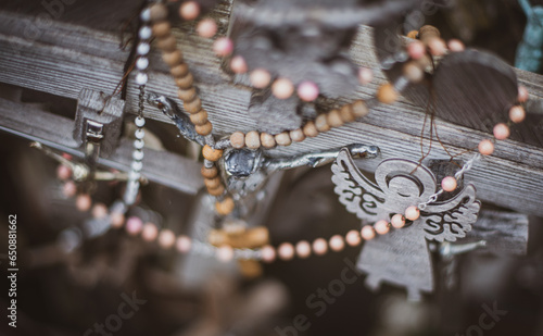 Closeup of necklaces and angel trinket around a wooden cross