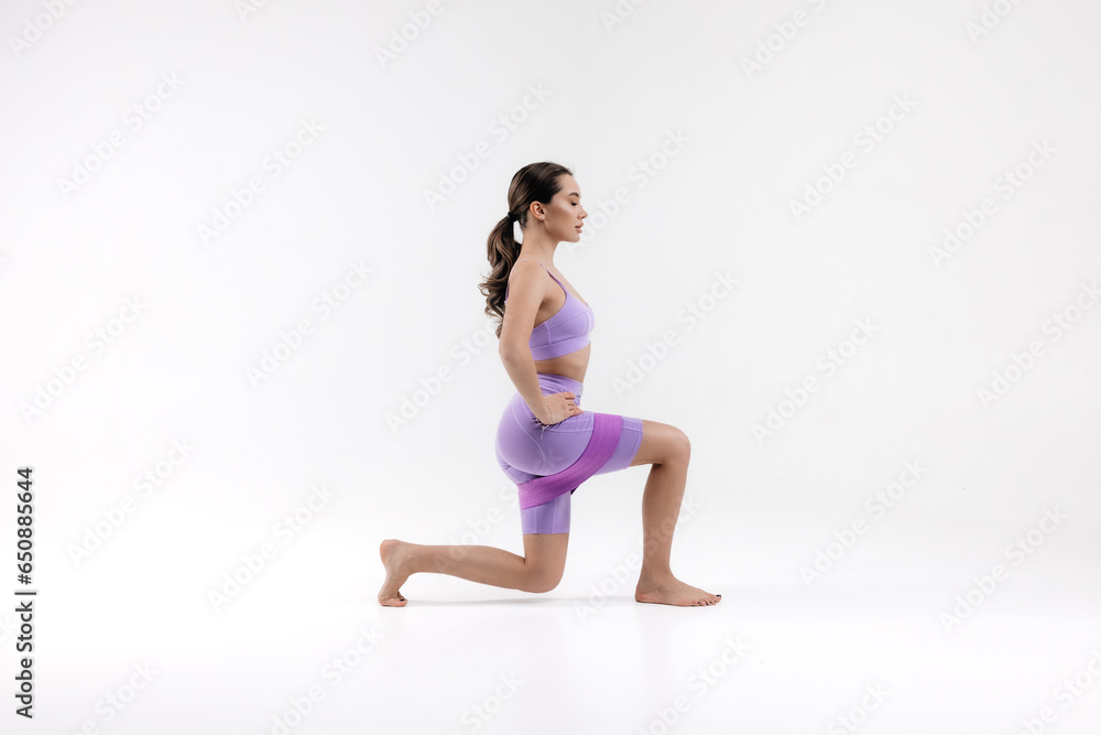 Sporty girl doing workout with rubber resistance band in motion. Photo of sporty girl with perfect body on white background. Strength and motivation
