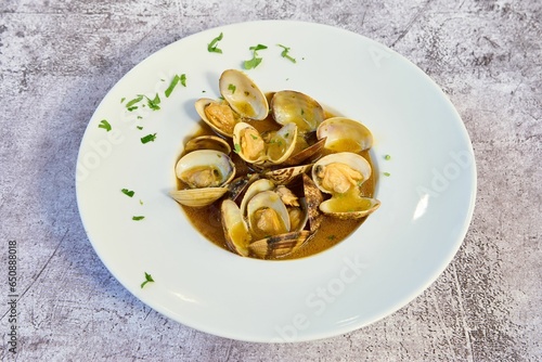 a dish of clams in a brown sauce with herbs
