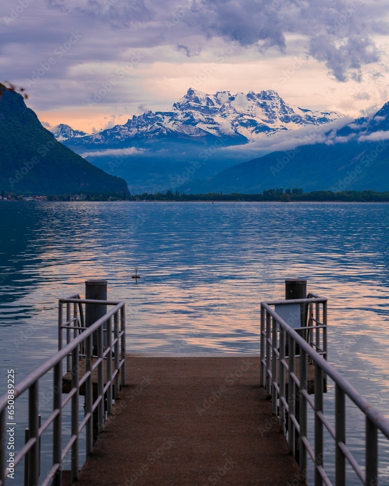 Obraz premium a dock with snow capped mountains in the background and a calm lake