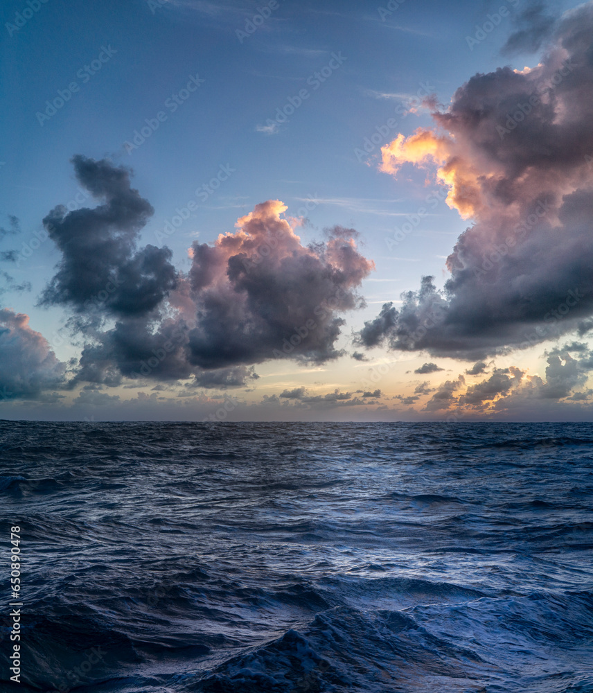Beautiful view of ocean waves under cloudy sky at sunset