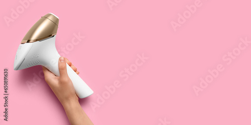 Hand with modern photoepilator on pink background with space for text