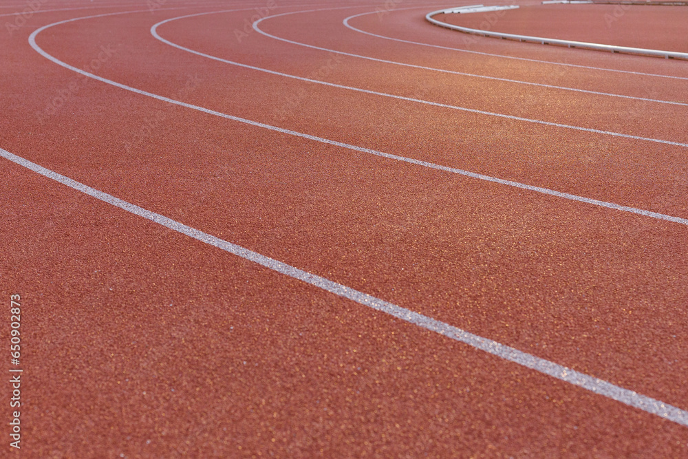 Close-up of the burgundy running track around the stadium illuminated by the morning light