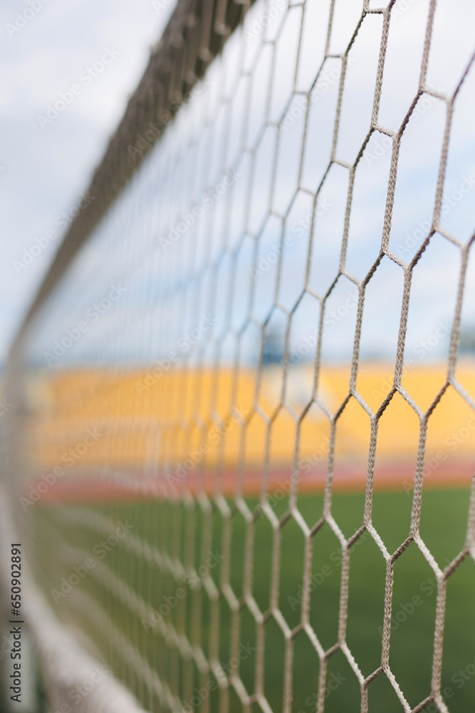 Close-up of soccer goal net in stadium against blue and yellow fan zone Close-up of soccer goal net in stadium against blue and yellow fan zone