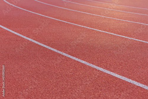 Close-up of the burgundy running track around the stadium illuminated by the morning light