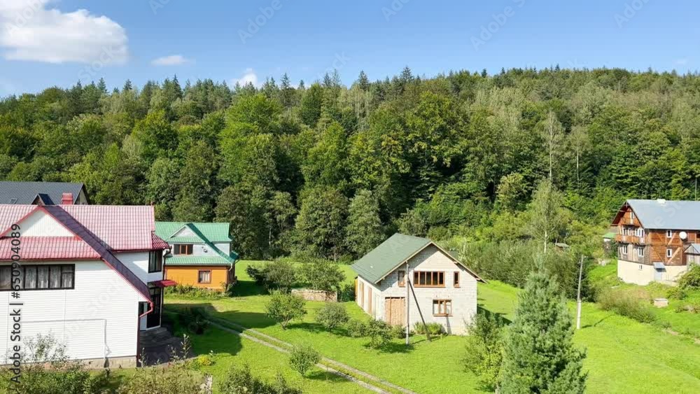 A view of beautiful houses in the middle of a forest green meadow on a sunny day. Private houses, cottages in nature in a mountainous area. Real estate for accommodation of tourists near the resort A view of beautiful houses in the middle of a forest green meadow on a sunny day. Private houses, cottages in nature in a mountainous area. Real estate for accommodation of tourists near the resort