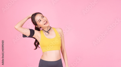 Cheerful sporty woman stretching body after sport over isolated pink background. Healthy active young girl sportswear with wireless earphones armband refreshing after sport stretch body looking empty. © kaew6566