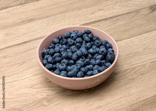 Blueberries in a bowl on a wooden background. Edited with Generative AI tools