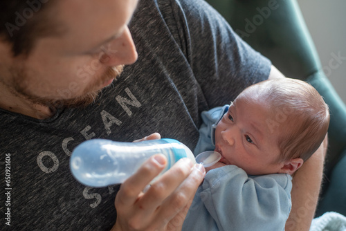 Father feeding his newborn baby with a silicone feeding bottle with spoon