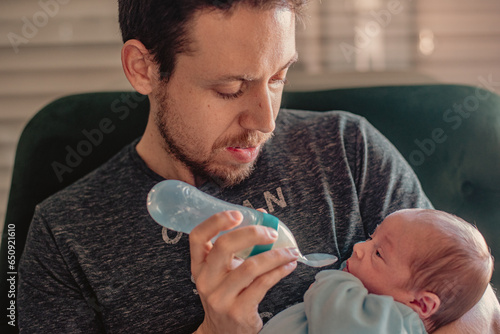 Father feeding his newborn baby with a silicone feeding bottle with spoon